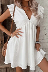 girl in white mini dress carring a brown purse